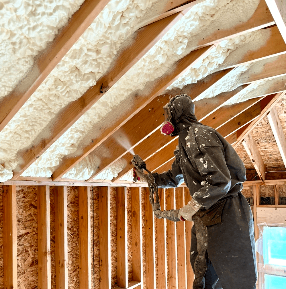 Worker spraying foam insulation in the attic.